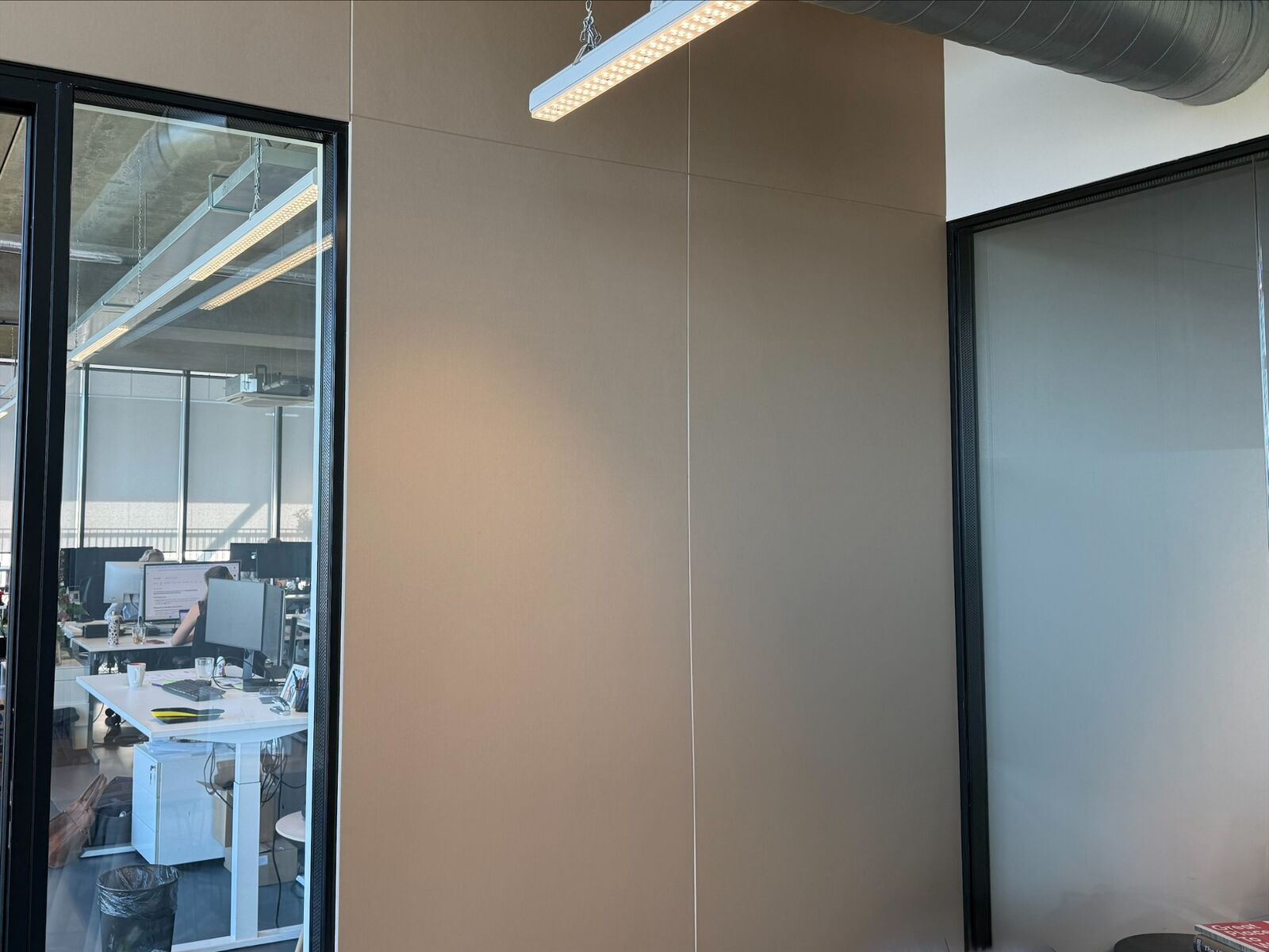 Detail van de beige wandafwerking en de paneelverdeling op deurhoogte.
