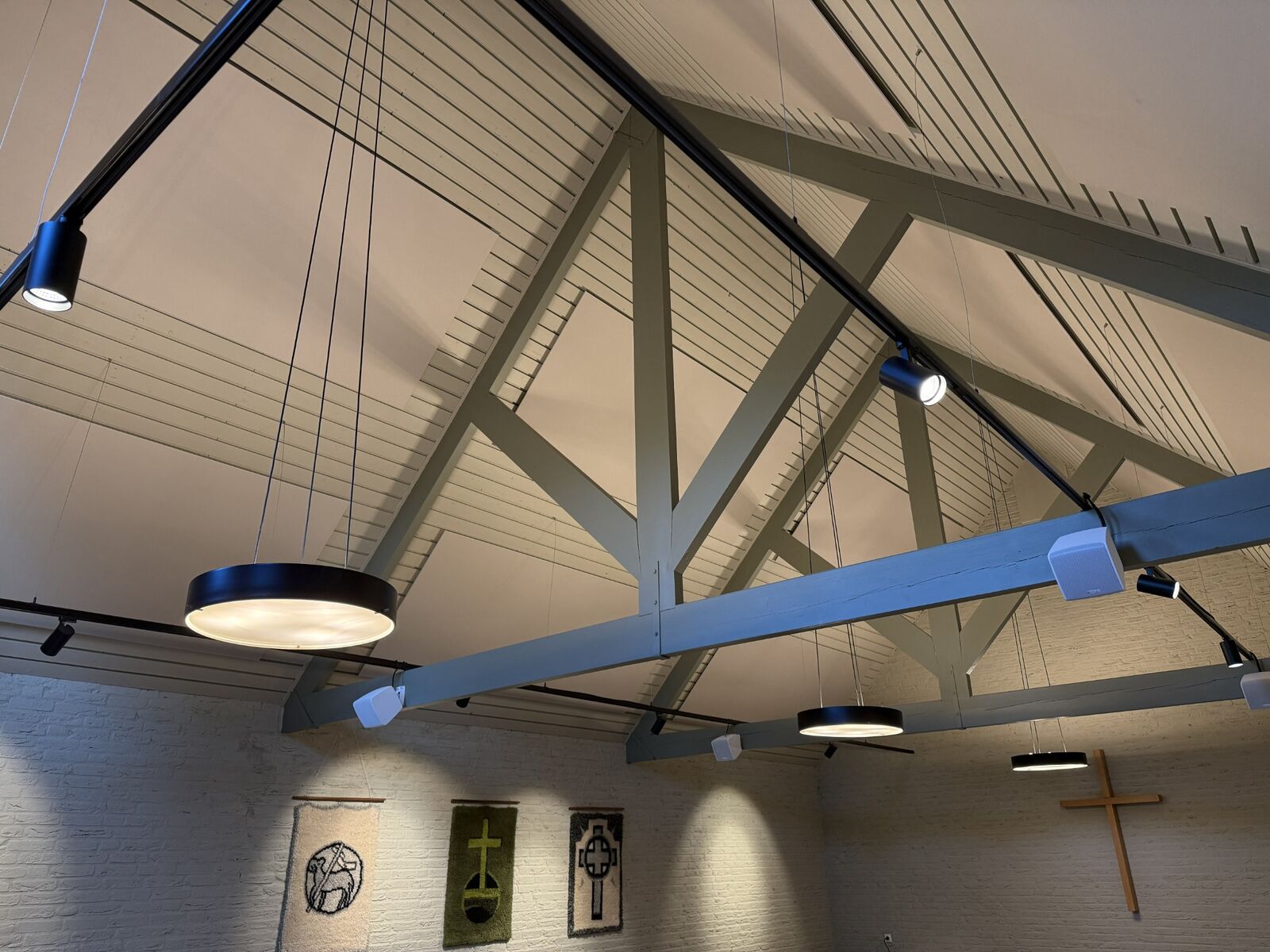 De plafondpanelen laten de houten draagconstructie en het karakter van de zaal zichtbaar.